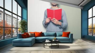 Young man with red book against split colored background Wall mural