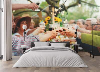 Cheerful Seniors Toasting at Countryside Gathering - A group of seniors raise their glasses in a cheerful toast at a country garden party. Wall mural