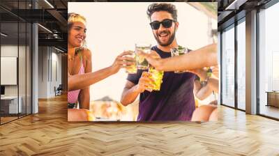 Group of young people making a beach party toasting with alcoholic drinks on the beach kiosk. Wall mural