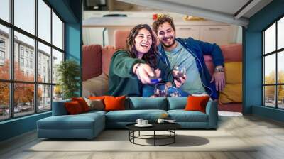 Happy caucasian young couple relaxing and watching comedy or funny movie on the TV at home sitting on the sofa. Wall mural