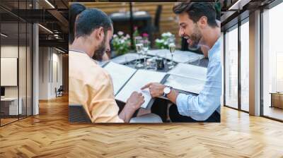 Two men discussing menu at outdoor restaurant - Friends choosing food and drinks on terrace Wall mural