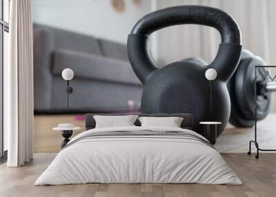 Kettlebell and dumbbell gym exercising equipment at home in the living room, next to the couch. Healthy fitness lifestyle. House exercise workout, indoor sport training concept. Wall mural