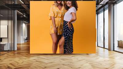 Amazing blonde girl in yellow outfit chilling with best friend. Indoor full-length shot of two enthusiastic sisters smiling to camera. Wall mural