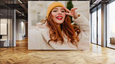 Appealing woman with ginger hair posing in cold winter day. Outdoor photo of beautiful red-haired girl. Wall mural