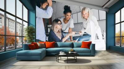 Asian young man scratching head and smiling while his female colleagues reading documents. Indoor portrait of cheerful students of international university preparing for test together. Wall mural