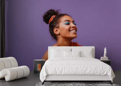 Blissful black woman in summer dress laughing on violet background. Adorable african girl in orange outfit posing with happy face expression. Wall mural