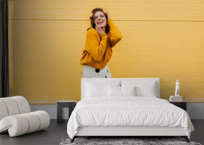 Blissful caucasian woman in trendy white skirt expressing happiness. Glad stylish girl posing on bright yellow background. Wall mural