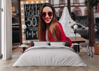 Charming european girl in trendy red attire spending time in cafe. Romantic white lady with straight hairstyle relaxing and drinking tea. Wall mural