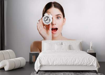 Close-up portrait of beautiful lady with white alarm clock covering her eyes. No makeup Wall mural