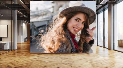 Close-up portrait of ecstatic white girl wears cute earrings and stylish gray hat. Photo of pretty caucasian woman in good mood spending time outdoor during travel in Europe. Wall mural