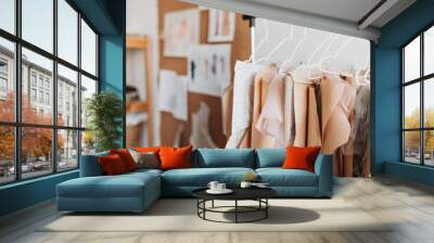 Clothing patterns hanging on hanger in white room. Snapshot of colored paper sheets with samples of new stylish garments Wall mural