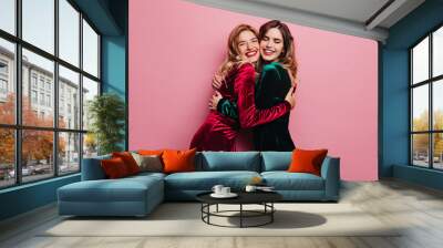 Excited female friends huggs on pink background. Indoor photo of blithesome adult sisters posing with smile. Wall mural