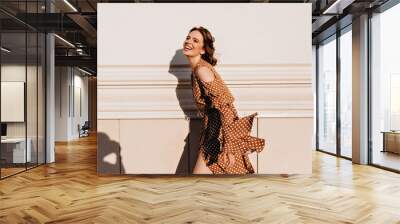 Excited spectacular woman posing in warm september day. Outdoor shot of laughing brown-haired girl in vintage dress. Wall mural