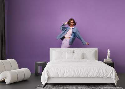 Full-length portrait of attractive slim girl wears white sport shoes. Indoor photo of enchanting caucasian woman dancing on violet background. Wall mural