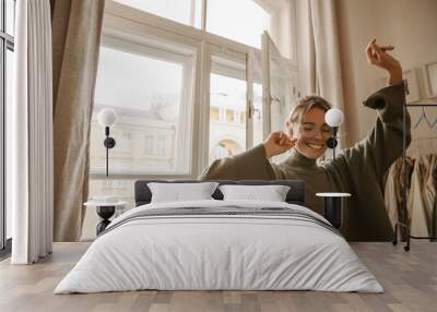 funny young fair-skinned woman dancing with her eyes closed alone at home in daytime. blonde with ha Wall mural