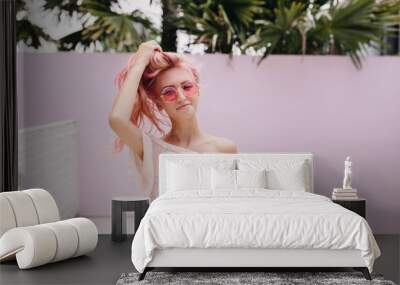 Funny young woman in summer attire chilling outdoor. Adorable girl with pink hair having fun on the street. Wall mural