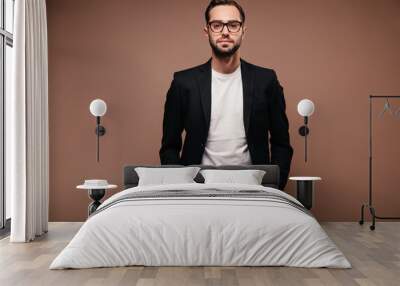 Guy in suit and glasses posing on brown background Wall mural