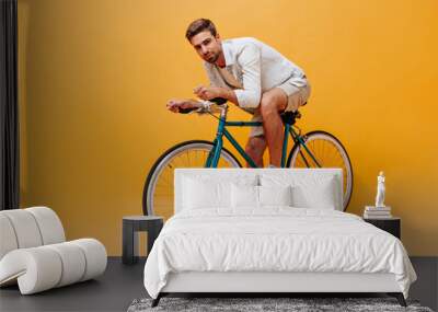 Handsome bearded man with brown hair in cool t-shirt and beige modern shorts posing with bicycle and looking into camera.. Wall mural