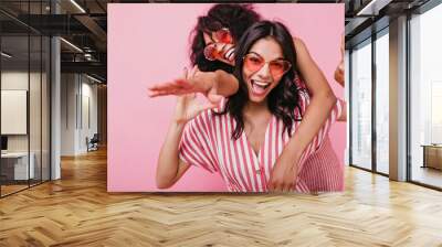 Happy, positive girls in light pink summer clothes, posing with sincere smile. Portrait of African models on gentle isolated background Wall mural