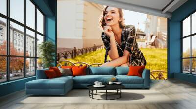 happy caucasian girl looking in distance while posing in park. refined short-haired woman in checker Wall mural