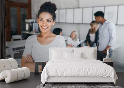 Pleased woman with light-brown skin posing with crossed arms and smiling, while people behind her working. Indoor portrait of tired students with laptop and african curly girl on foreground. Wall mural