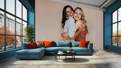 Pretty girls with trendy makeup embracing on light background. Excited caucasian sisters expressing love. Wall mural