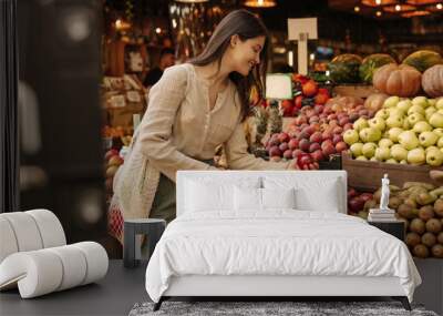 Pretty young caucasian brunette woman at fair chooses fresh ripe fruits. Girl is looking for good option for her diet. Healthy food concepts Wall mural