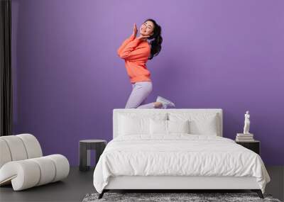 Refined asian woman standing on one leg. Full length view of blissful chinese girl dancing on purple background. Wall mural