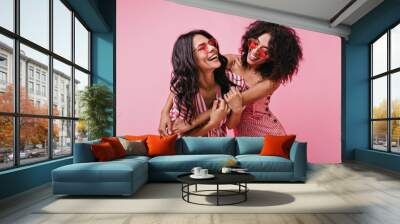 Romantic shot in cute studio of two tender young girls. Cheerful, naughty models with dark skin and curls rejoice excellent photo shoot Wall mural