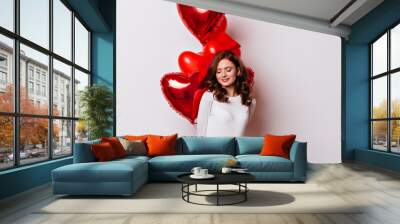 Shy ginger girl posing in valentine's day. Studio photo of attractive woman with balloons isolated on white. Wall mural