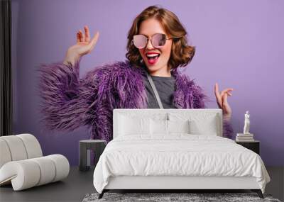 stunning cute girl with curly brown hair posing with pleasure on purple background. indoor photo of  Wall mural