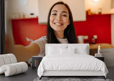 Woman in great mood takes selfie in kitchen. Portrait of brown-eyed girl Wall mural