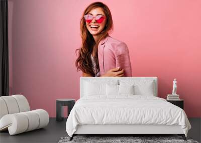 Wonderful young woman with long hair having fun on rosy background. Magnificent girl in trendy sunglasses relaxing during photoshoot. Wall mural