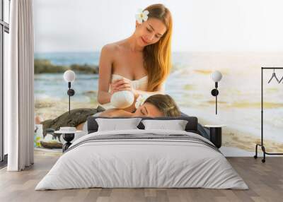 Asian woman are happy and relaxed massage at a spa on the beach in the evening. Wall mural