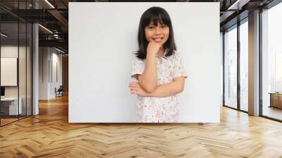 Beautiful kid girl with straight hair wearing pajama looking confident at the camera with smile with crossed arms and hand raised on chin. thinking positive. Wall mural