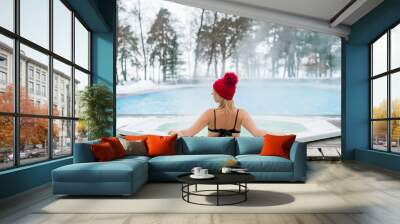 Young blonde woman in red hut in bathtub jacuzzi outdoors at winter day Wall mural