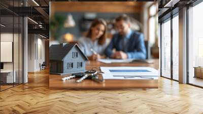 Real estate agent shows a house model to customer at table in office. Wall mural