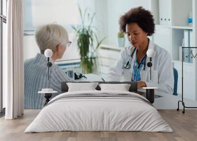 A female doctor sits at her office and examining elderly female patient Wall mural