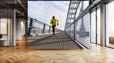 Attractive fit man running fast along big modern bridge. Exercising, Jogging, Sport, Winter. Male athlete running. Wall mural