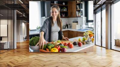 Beautiful smiling young pregnant woman preparing healthy food with lots of fruit and vegetables at home kitchen Wall mural