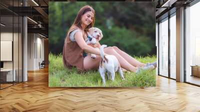 Beautiful young girl playing with a puppy labrador in the park  Wall mural