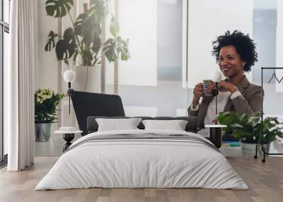 Happy smiling african-american business woman working on laptop at office. Businesswoman sitting at her working place Wall mural