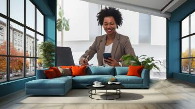 Happy smiling african-american business woman working on laptop at office. Businesswoman sitting at her working place Wall mural