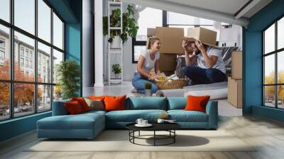 Happy young couple unpacking or packing boxes and moving into a new home  Wall mural