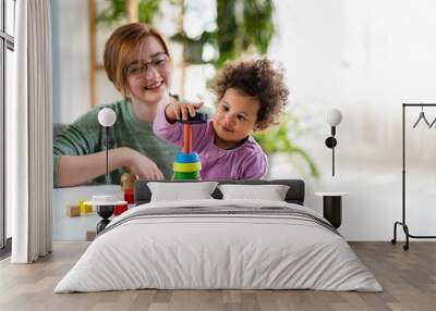 Mother looking at a child playing with an educational didactic toy. Preschool teacher with a child playing with didactic toys Wall mural