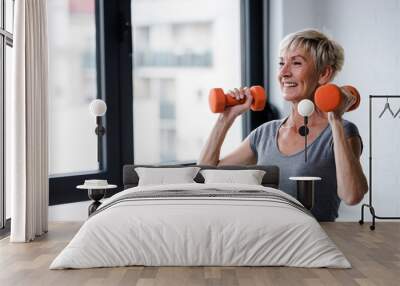 Portrait of senior woman lifting dumbbells Wall mural