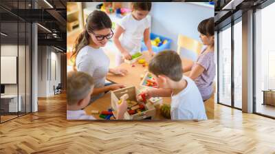 Preschool teacher with children playing with colorful wooden didactic toys at kindergarten Wall mural