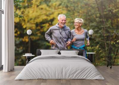 Smiling senior couple jogging in the park Wall mural