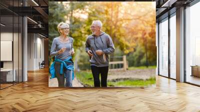 Smiling senior couple jogging in the park Wall mural