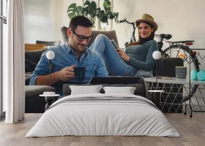 Young Caucasian couple using mobile devices for work from home. Social distancing and remote work concept. Wall mural